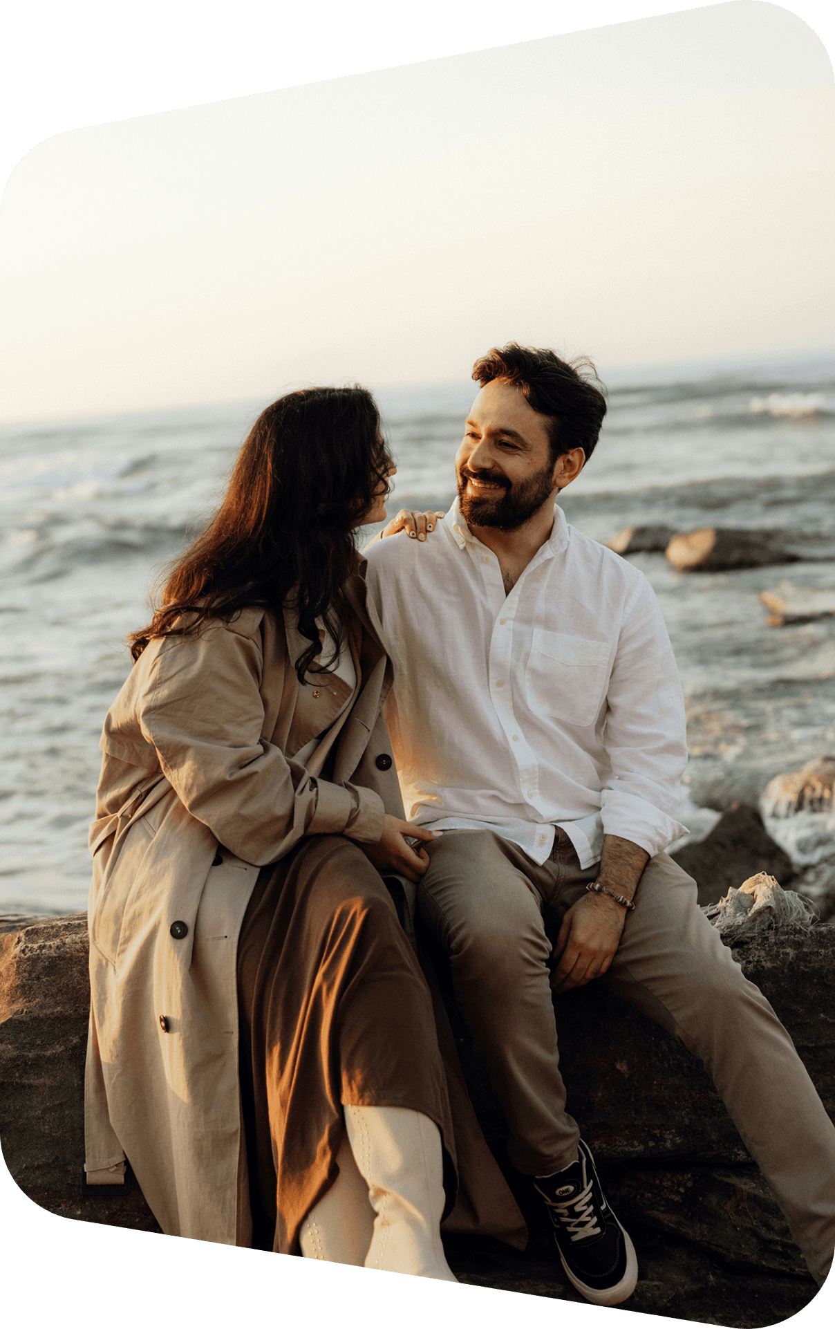 A couple sitting together by the sea at sunset